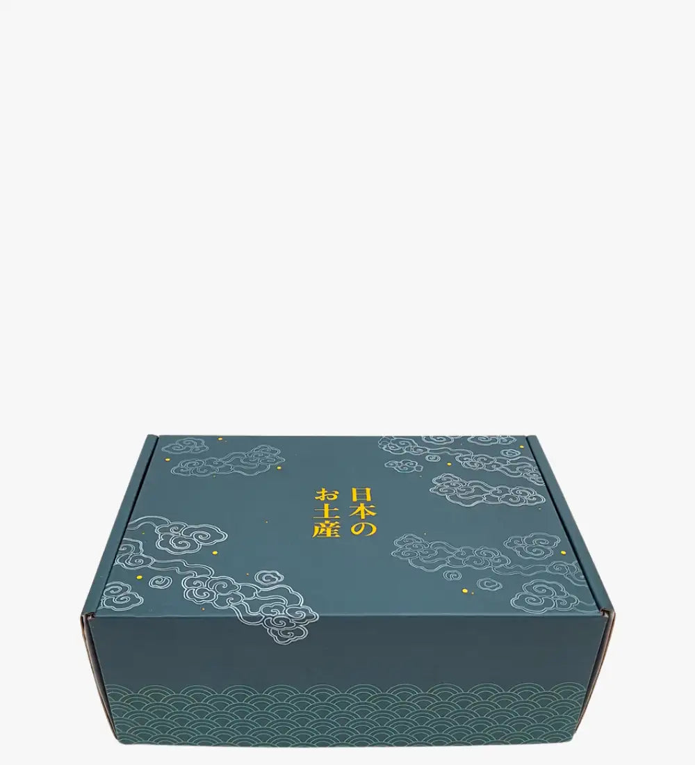 Teal kartongpresentlåda prydd med vita moln- och vågmönster, med guldiga japanska tecken.